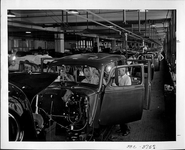 Packard factory assembly line, workers inside bodies installing interior parts