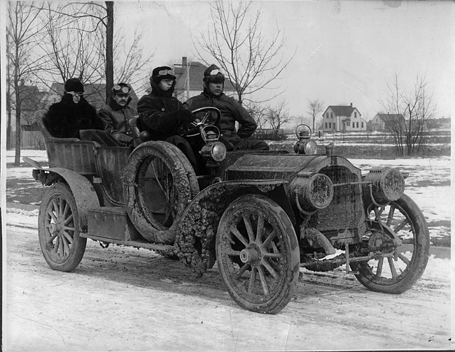 1908 Packard model U test car covered in mud with four male passengers