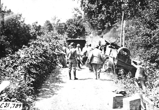 Group of men pulling a car out of a ditch at the side of a rural road, at 1909 Glidden Tour