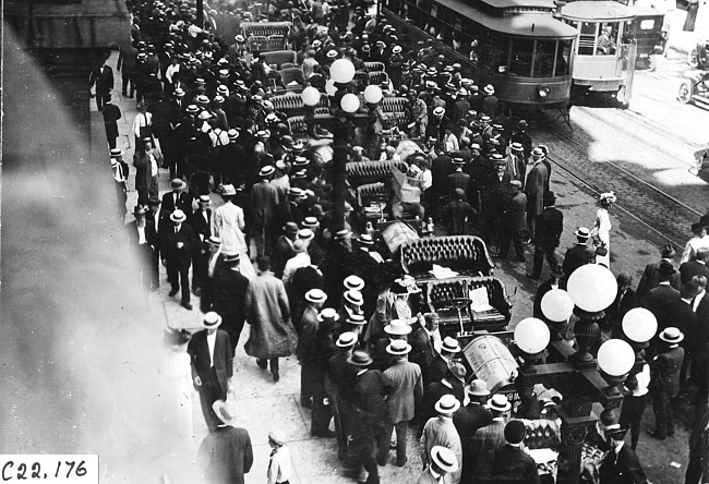 Bird's eye view of crowd surrounding 'tourist' cars in Rochester, Minn., at the 1909 Glidden Tour