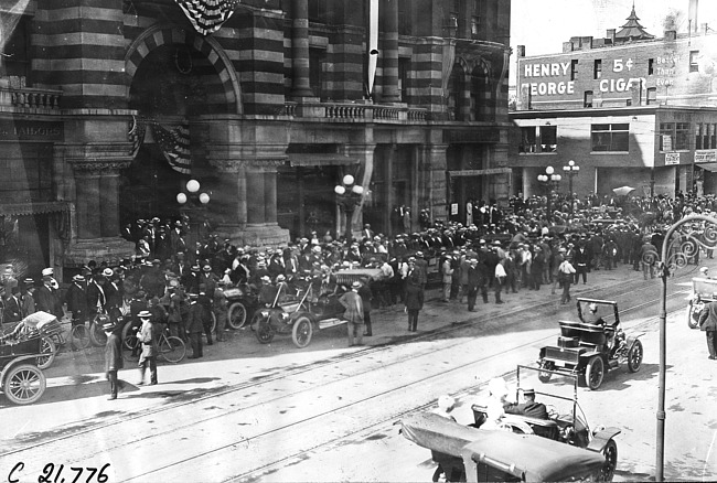 Bird's eye view of large crowd welcoming Glidden tourists at the Hotel West in Rochester, Minn., at the 1909 Glidden Tour
