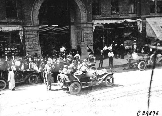 Bird's eye view of crowd watching in front of the West Hotel in Rochester, Minn. as Glidden tourists leave, at the 1909 Glidden Tour