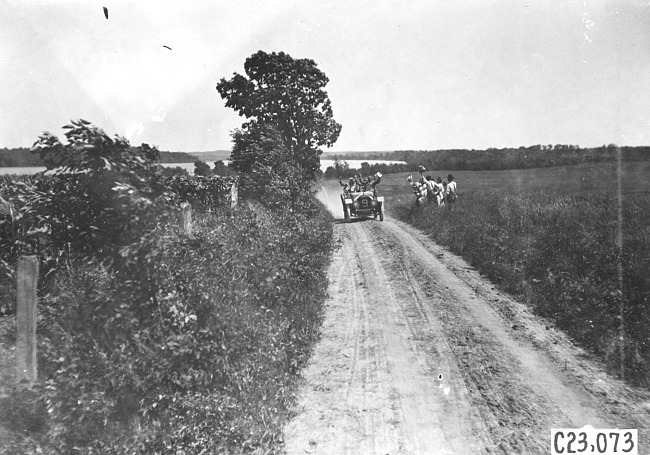 Driver and passengers in car #9 wave to group in field near Wood River, Neb., at 1909 Glidden Tour