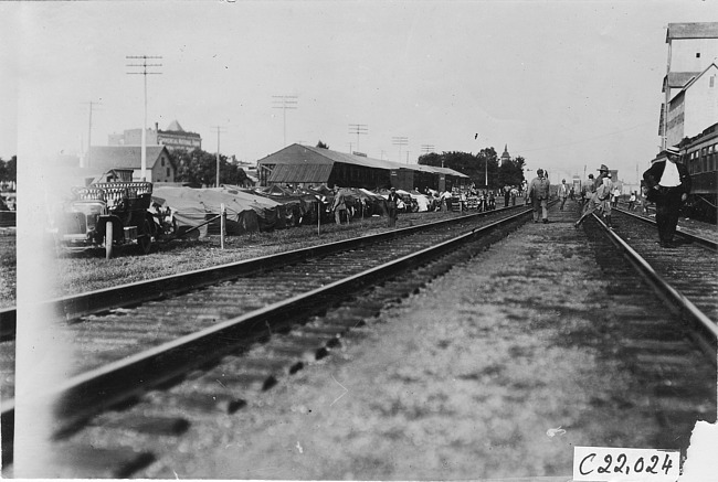 Line up of covered tourist vehicles parked near railroad tracks in Kearney, Neb., at 1909 Glidden Tour
