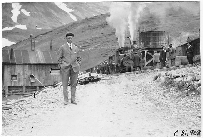 H.W. Ford on mountain road, train in background at Waldorf, Colo., at 1909 Glidden Tour