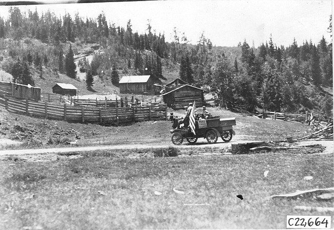 Rapid motor truck on mountain road near house in Colo., at 1909 Glidden Tour