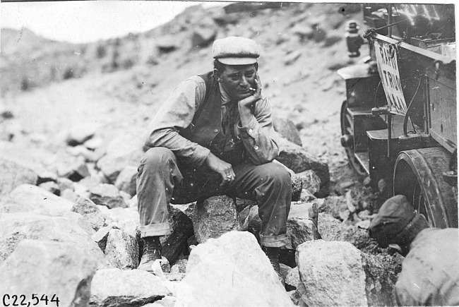 Glidden tourist sits next to Rapid motor truck stuck in the rocks in Colo., at 1909 Glidden Tour