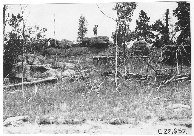 Glidden tourist standing on boulder in Colorado mountains, at 1909 Glidden Tour