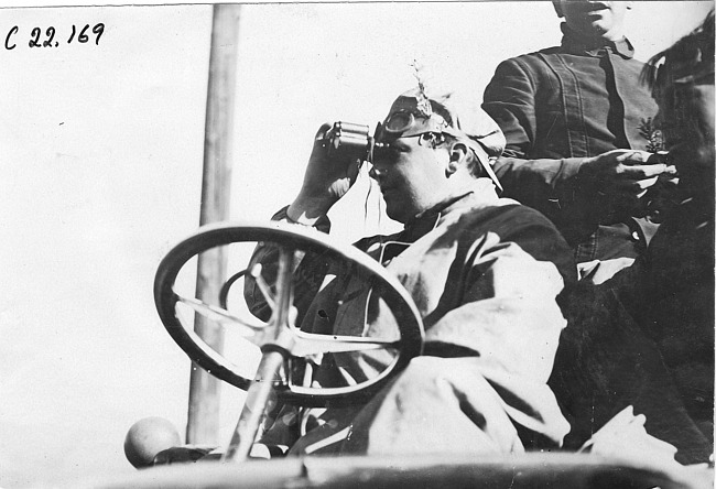 Harry McIntosh looks through binoculars in Colo., at 1909 Glidden Tour