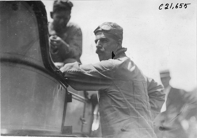 Glidden tourist leans against car, at 1909 Glidden Tour