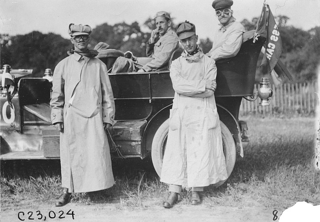 Glidden tourists posed in full length driving coats, hats and goggles, at 1909 Glidden Tour
