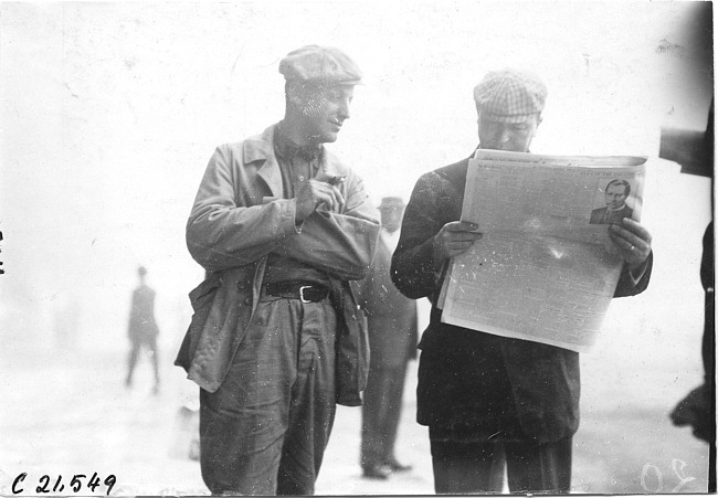 Two reporters read newspaper, at 1909 Glidden Tour
