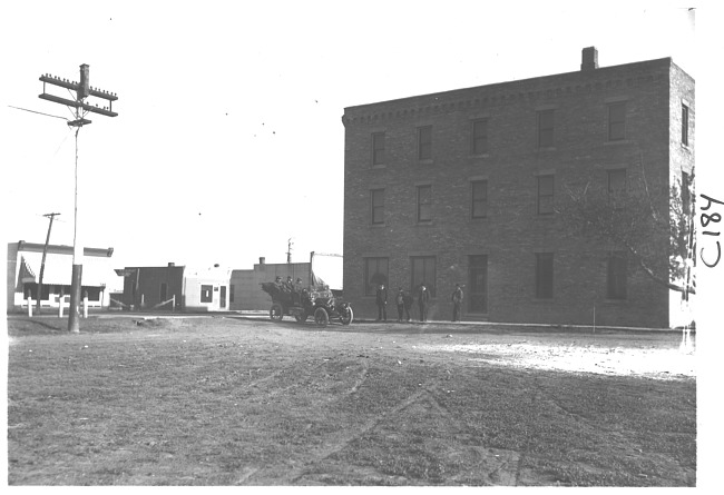 E.M.F. car parked in front of large brick building, on pathfinder tour for 1909 Glidden Tour