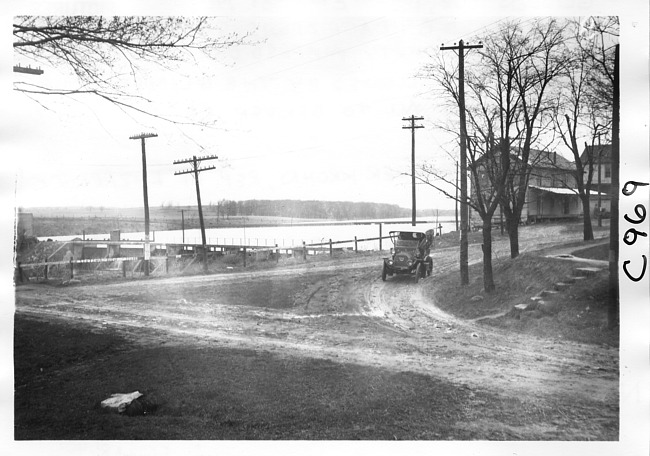 E.M.F. car rounding corner by lake, on pathfinder tour for 1909 Glidden Tour