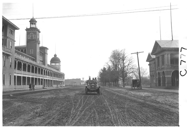 E.M.F. car passing building with belfry, on pathfinder tour for 1909 Glidden Tour