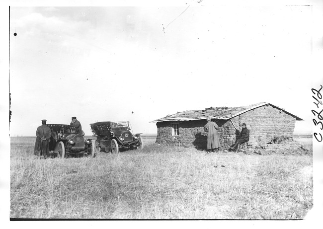 E.M.F. car and another vehicle parked next to sod house, on pathfinder tour for 1909 Glidden Tour