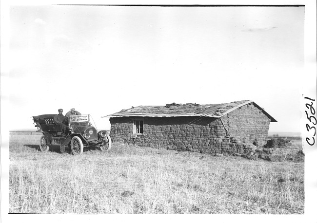 E.M.F. car parked next to sod house, on pathfinder tour for 1909 Glidden Tour