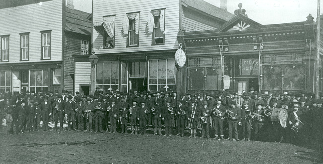Iron Mountain band in front of Rundle Bros. Hardware & Seibert's Drug Store