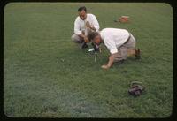 Two Toro Corporation engineers take a close-up photograph on a turf surface at the Toro Research Center, Toro Headquarters, Minnesota, 1953