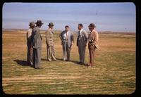 Six men, including Dr. James Watson, in discussion stand on a striated turf at Midland Country Club, Texas, 1951