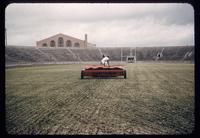Onfield view looking towards endzone of a football field being topdressed with peat using an Ezee Flow drop spreader, 1952