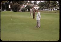 Severely countoured golf green at the La Gorce Country Club, Miami Beach, 1953, with 3 men indicating elevation variations