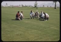 Six stooping men discuss turf conditions on a bermudagrass fairway at the Desert Inn Golf Club, Las Vegas, 1954